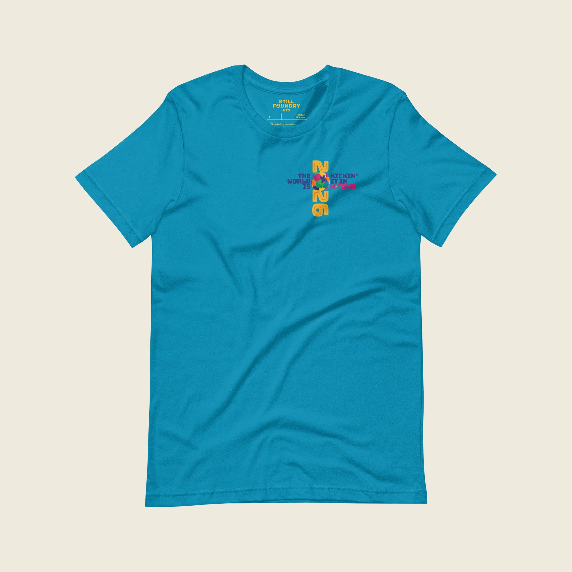 Front view of aqua Houston 2026 T-shirt with small “Kickin’ It in H-Town” chest graphic.