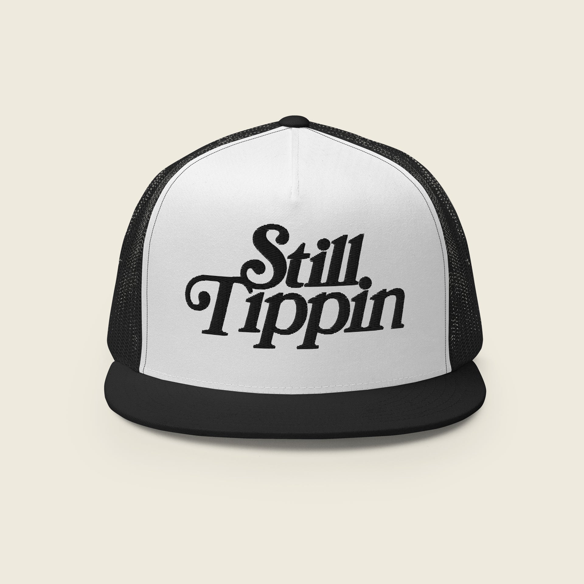 White and black trucker snapback hat with the phrase "Still Tippin" embroidered in bold black script on the front white panel. The hat features a black bill and black mesh backing.