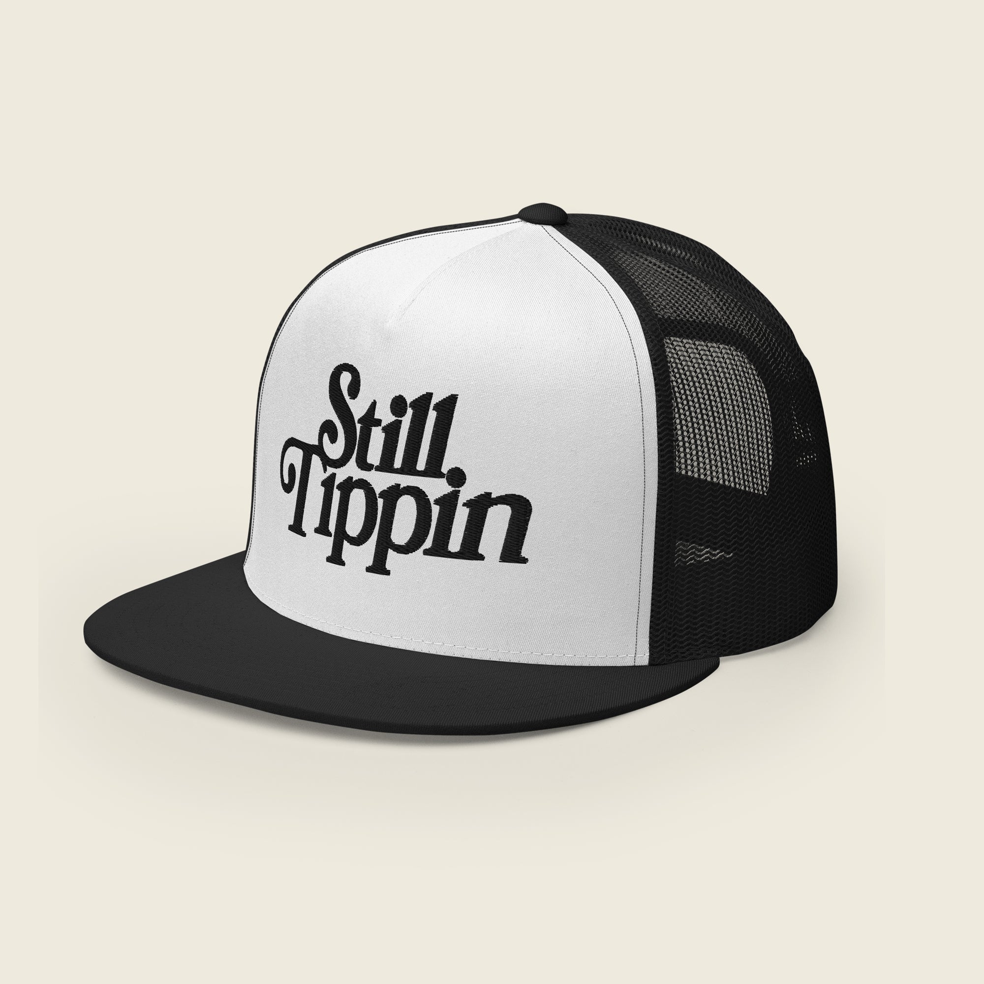 White and black trucker snapback hat with the phrase "Still Tippin" embroidered in bold black script on the front white panel. The hat features a black bill and black mesh backing.